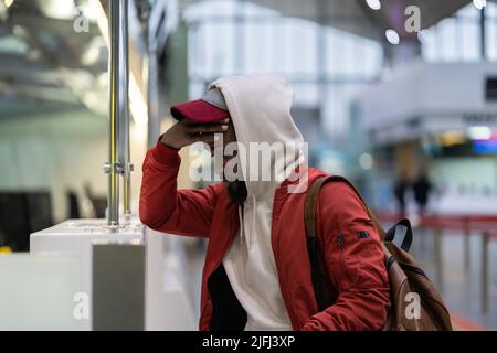 Il triste uomo africano che si trova vicino al banco del check-in si sente frustrato a causa della cancellazione del volo Foto Stock