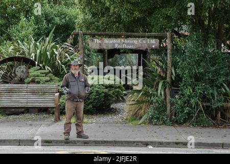 Reefton Nuova Zelanda - Maggio 4 2022; l'uomo Bearded vestito come pioniere si trova in strada fuori l'ingresso alla Bearded Mining Company attrazione turistica Foto Stock