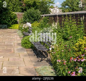 Due panchine di legno in un giardino di fiori in città di proprietà Mellon Park a Pittsburgh, Pennsylvania, Stati Uniti d'America in una soleggiata giornata estiva Foto Stock