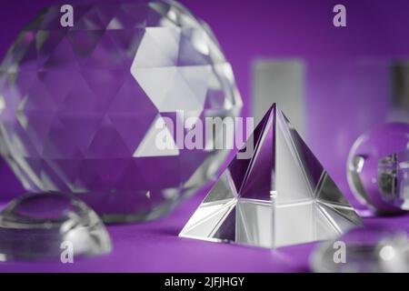 Luce rifrangente a prisma di cristallo, cristalli magici e piramide, sfera e cubo su sfondo viola. Pratica di cristallo di guarigione spirituale. Feng Shui, bravo Foto Stock