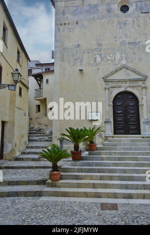 Un colpo verticale di ingresso chiesa circondato da edifici e piante a Scalea Foto Stock