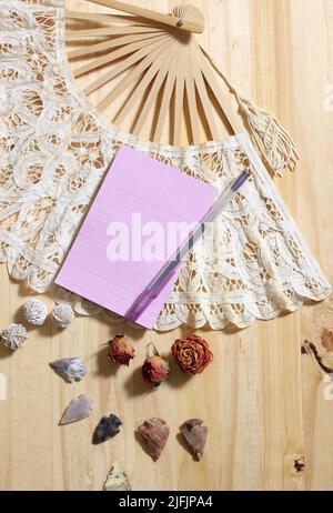 Notepaper su Vintage Lace Fan con rose secche e frecce native americane su sfondo di legno Foto Stock