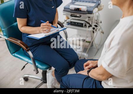 Il primo piano dello specialista ecografico medico prende appunti durante l'appuntamento del paziente in clinica Foto Stock