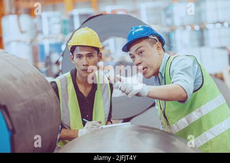 Il team di assistenza per lavoratori del settore pesante che lavora in una fabbrica di metallo. Foto Stock