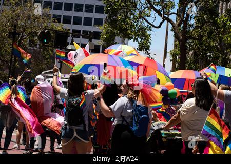 Le persone che partecipano alla sfilata d'orgoglio in città, con bandiere arcobaleno e ombrelloni. Foto scattata a San Francisco, Stati Uniti d'America il 26 2022 giugno Foto Stock
