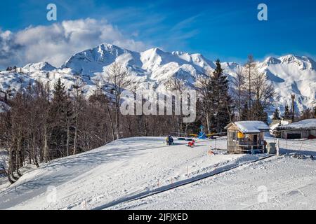 Bohinj, Slovenia - Rifugio in legno presso la stazione sciistica di Vogel a Bohinj, nelle Alpi Giulie, in una soleggiata giornata invernale con cielo blu e nuvole Foto Stock