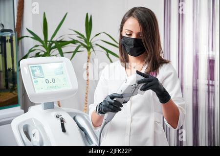 Clinica di medicina estetica. Cosmetologo in maschera protettiva e guanti dispositivo di preparazione per la ricezione di pazienti che hanno assegnato la procedura SMAS sollevamento da ultraformer. Foto Stock