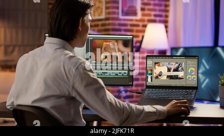 Videografo asiatico che modifica filmati multimediali su pc, utilizzando il software di effetti visivi sul display. Sviluppo di video montaggio con gradiente di colore, creazione di contenuti professionali. . Foto Stock