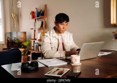 Giovane uomo asiatico sul cellulare bere caffè Foto Stock