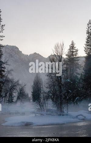 La valle di Yosemite è circondata da un sottile strato di nebbia che si estende sul fiume merced, fornendo un'atmosfera inquietante intorno al tramonto. Foto Stock