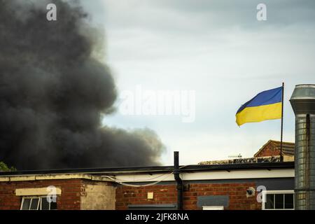 Bandiera Ucraina che sventola sul fumo nero Foto Stock