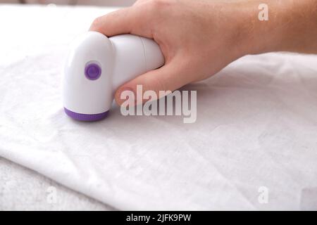 L'uomo rimuove i pelucchi utilizzando un rasoio con lanugine. Foto Stock