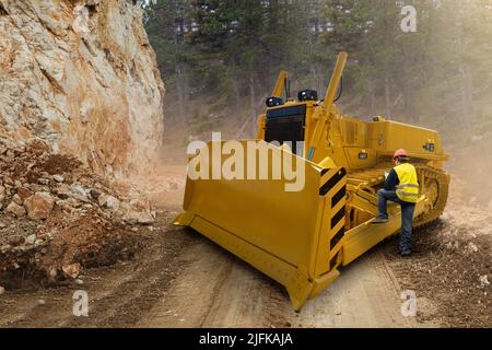 L'ingegnere programma un bulldozer autonomo utilizzando un tablet digitale Foto Stock