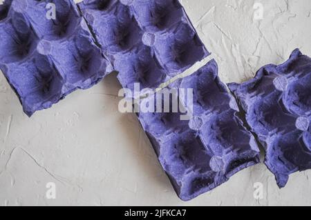 Vista dall'alto di cartoni vuoti di uova, di colore blu-viola, da riciclare, su sfondo bianco, scatole di uova Foto Stock