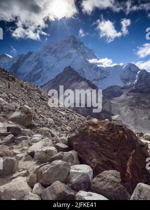 Gli escursionisti seguono il sentiero roccioso lungo la morena del ghiacciaio di Khumbu sotto Nuptse Nup II (7732m) sul percorso dell'Everest base Camp vicino a Gorak Shep. Foto Stock