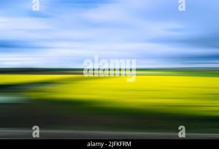 Immagine sfocata e scossa di un paesaggio in sfumature di verde, giallo e blu da utilizzare come modello o sfondo. Foto Stock