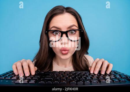 Primo piano ritratto di divertente focalizzato femmina lavoro sul nuovo progetto digitando tastiera isolato su sfondo blu Foto Stock