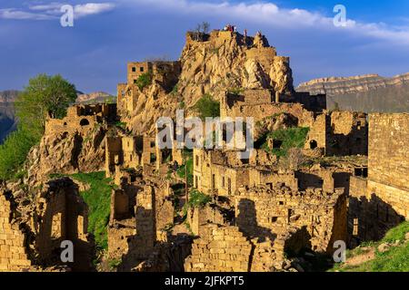 Gamsutl, Russia - 15 maggio 2022: Vista del villaggio abbandonato sulla cima di una montagna in Dagestan, con i turisti tra le rovine Foto Stock