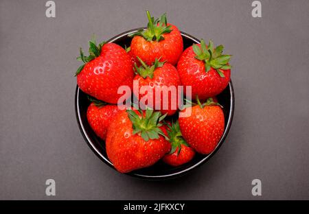 fragole inglesi appena raccolte in ciotola su sfondo marrone Foto Stock