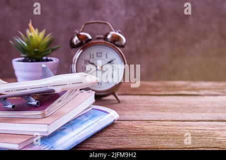 Sveglia retrò, aereo, mappa e notebook su un tavolo di legno. Foto in stile immagine a colori retrò. Vista dall'alto con spazio di copia per l'uso. Foto Stock