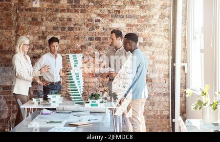 Gruppo di diversi architetti che discutono di piani, progetti e schemi durante una riunione nella sala riunioni dell'ufficio. Business persone brainstorming e. Foto Stock