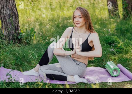 Yoga donna su erba verde ragazza si rilassa nel campo. Yoga donna in verde parco ragazza che fa la ginnastica all'aperto. Meditando la donna in meditazione nelle pratiche di posa yoga all'aperto Foto Stock