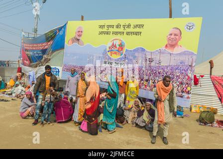 Pellegrini sotto giganteschi cartelloni, Allahabad Kumbh Mela, più grande del mondo di raccolta religiosa che, Uttar Pradesh, India Foto Stock