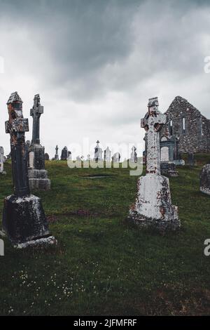 Un colpo verticale di croci celtiche in un cimitero al monastero di Clonmacnoise. Contea di Offaly, Irlanda Foto Stock