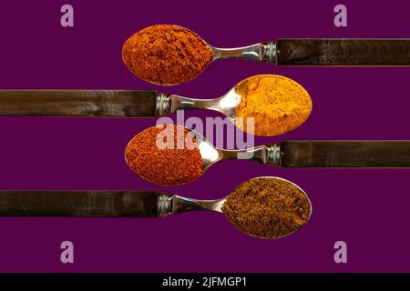 Una selezione di cayenne pepe curcuma peperoncino curry spezie in polvere utilizzato in cucina indiana su un colorato sfondo viola Foto Stock