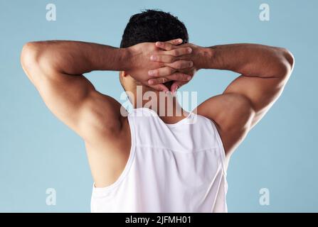 Giovane uomo da corsa misto retravista che indossa un gilet in studio isolato su sfondo blu. Atleta maschio irriconoscibile in piedi con le mani dietro Foto Stock