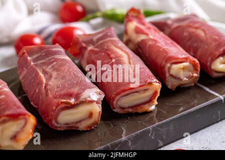 Pastrami al formaggio. Pastrami ripieni di cheddar, pancetta alla griglia su un pavimento di pietra. Carne preparata appositamente per barbecue. Primo piano Foto Stock