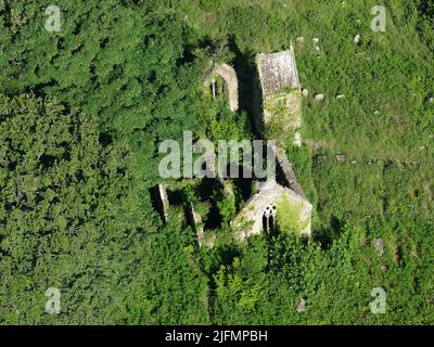 VISTA AEREA. Abbandonata chiesa di Santa Maria e cimitero cresciuto dalla vegetazione. Tintern, Monmouthshire, Galles, Regno Unito. Foto Stock