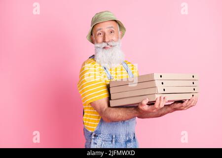 Foto di sorridente buon umore consegna uomo tenere mucchio di pizza in scatola di cartone cibo malsano isolato su sfondo rosa Foto Stock