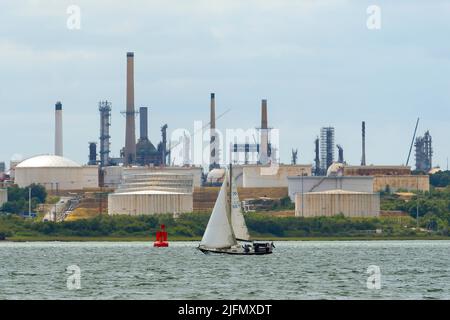 Fawley, Hampshire, Regno Unito. 4th luglio 2022. Vista generale della raffineria di olio di Fawley che si trova sulle rive di Southampton Water vicino Southampton in Hampshire che è di proprietà della esso Petroleum Company. Nella foto è raffigurato uno yacht che naviga verso il Solent oltre la raffineria. Picture Credit: Graham Hunt/Alamy Live News Foto Stock