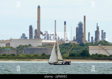 Fawley, Hampshire, Regno Unito. 4th luglio 2022. Vista generale della raffineria di olio di Fawley che si trova sulle rive di Southampton Water vicino Southampton in Hampshire che è di proprietà della esso Petroleum Company. Nella foto è raffigurato uno yacht che naviga verso il Solent oltre la raffineria. Picture Credit: Graham Hunt/Alamy Live News Foto Stock