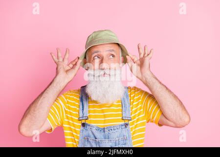 Foto di funky divertente nonno in sunhat guardare copyspace pensare brainstorming godere l'estate isolato su sfondo di colore rosa Foto Stock