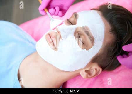 Uomo con maschera antiage in ufficio cosmetologia Foto Stock