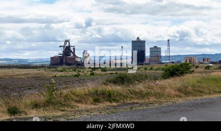 L'ex SSI altoforno visto da South Gare a Redcar, Inghilterra, Regno Unito con erba in primo piano Foto Stock