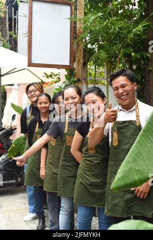 Il personale della caffetteria vietnamita sorride e si alza insieme contro un caffè Foto Stock