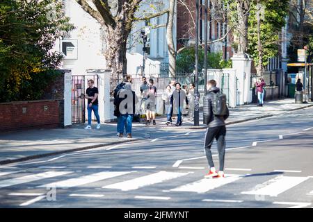 La gente si raduna intorno all'incrocio della zebra di fronte agli Abbey Road Studios di Londra. Foto Stock