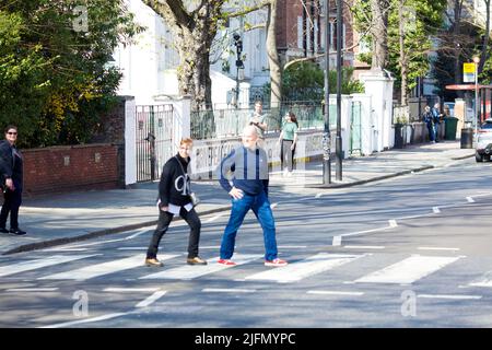 La gente si raduna intorno all'incrocio della zebra di fronte agli Abbey Road Studios di Londra. Foto Stock
