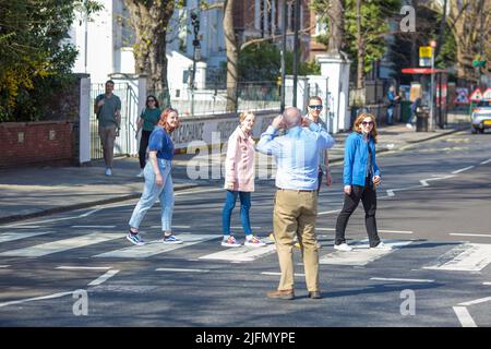 La gente si raduna intorno all'incrocio della zebra di fronte agli Abbey Road Studios di Londra. Foto Stock