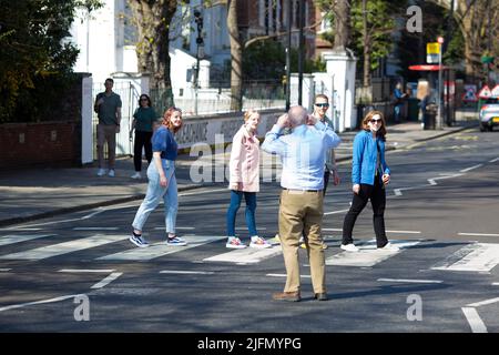 La gente si raduna intorno all'incrocio della zebra di fronte agli Abbey Road Studios di Londra. Foto Stock