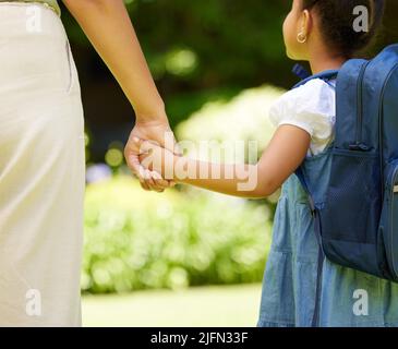 Avere una famiglia meravigliosa come la mia è veramente una benedizione. Scatto corto di una bambina che tiene la mano delle madri mentre cammina fuori. Foto Stock