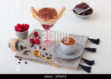 Tiramisù di lamponi fatto in casa veloce per una visita inaspettata, dolce senza torta dessert stile cheesecake con ingredienti posti su tavola bianca di legno. Foto Stock