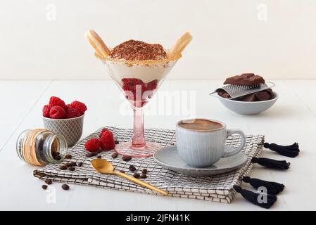 Tiramisù di lamponi fatto in casa veloce per una visita inaspettata, dolce senza torta dessert stile cheesecake con ingredienti posti su tavola bianca di legno. Foto Stock