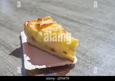 pezzo di torta di mele fresche con mandorle su un cartone su un tavolo al sole, delizioso dessert estivo, spazio copia, fuoco selezionato, stretta profondità di fiel Foto Stock