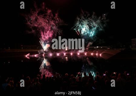 Fuochi d'artificio in rosso e blu riflessi nell'acqua e molte persone nella notte oscura sono guardare, vacanza e festival concetto, spazio copia, selezionato fo Foto Stock