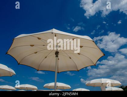 Ombrelloni bianchi aperti in una bella giornata di sole Foto Stock