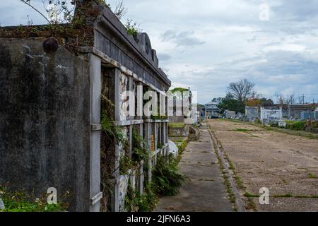 NEW ORLEANS, LA, USA - 15 GENNAIO 2022: Vecchia cripta allo storico Carrollton No. 1 Cimitero con tombe e quartiere in background Foto Stock